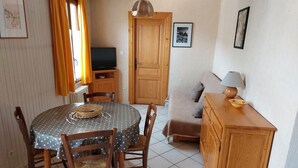 A compact living space with a dining table, chairs, a sofa, a TV, and a cabinet. - Spacious 2-room for 4 people, pets allowed (Valloire)