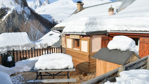 A wooden chalet with a wooden deck and snow-covered roof, surrounded by snow-covered mountains. - 3* Apartment for 8 people, pets allowed, parking (Valloire)
