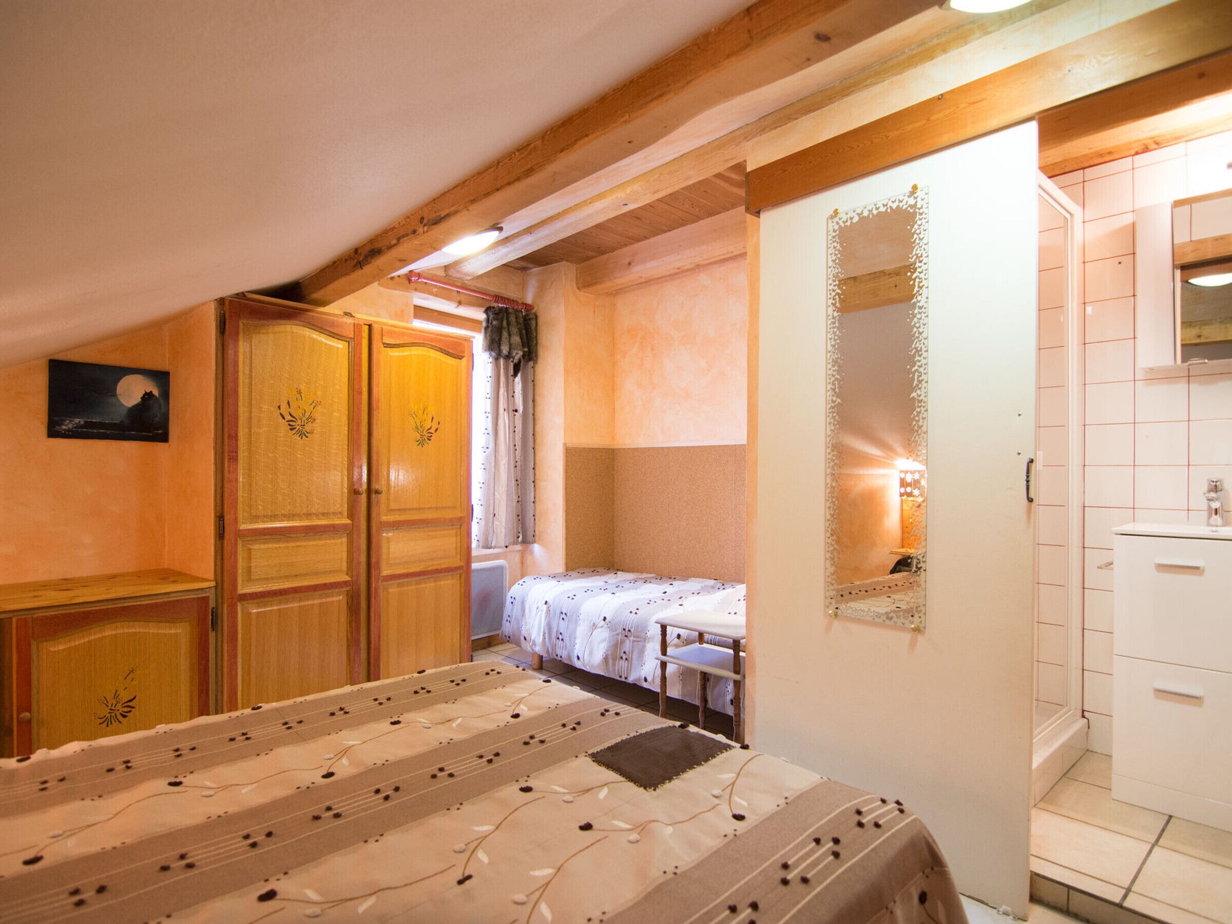 A bedroom with a bed, wooden wardrobe, and a small table.