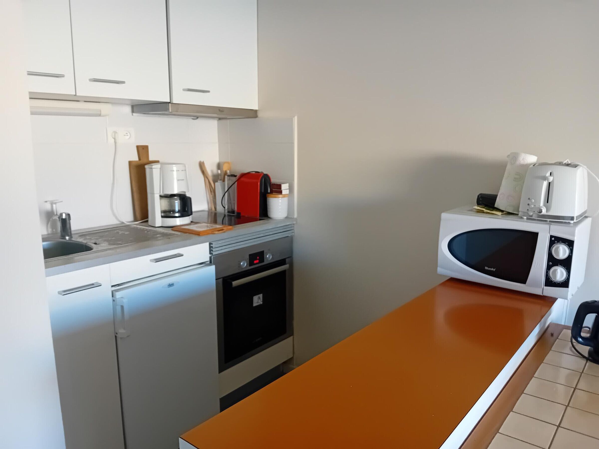 A compact kitchen with a sink, a coffee maker, a toaster, and a microwave.