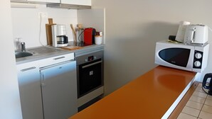 Una cocina compacta con un lavabo, cafetera, tostadora y microondas.