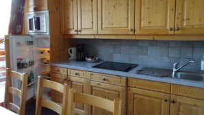 Una cocina con armarios de madera, microondas, cafetera y pileta.