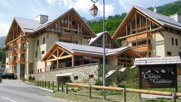 Un hotel de estilo chalet con varios balcones de madera y fachada de piedra.