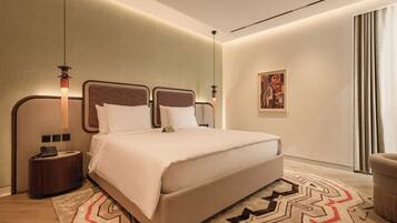 Una habitación de hotel moderna con una cama grande, mesitas de noche, un escritorio y un cuadro en la pared.