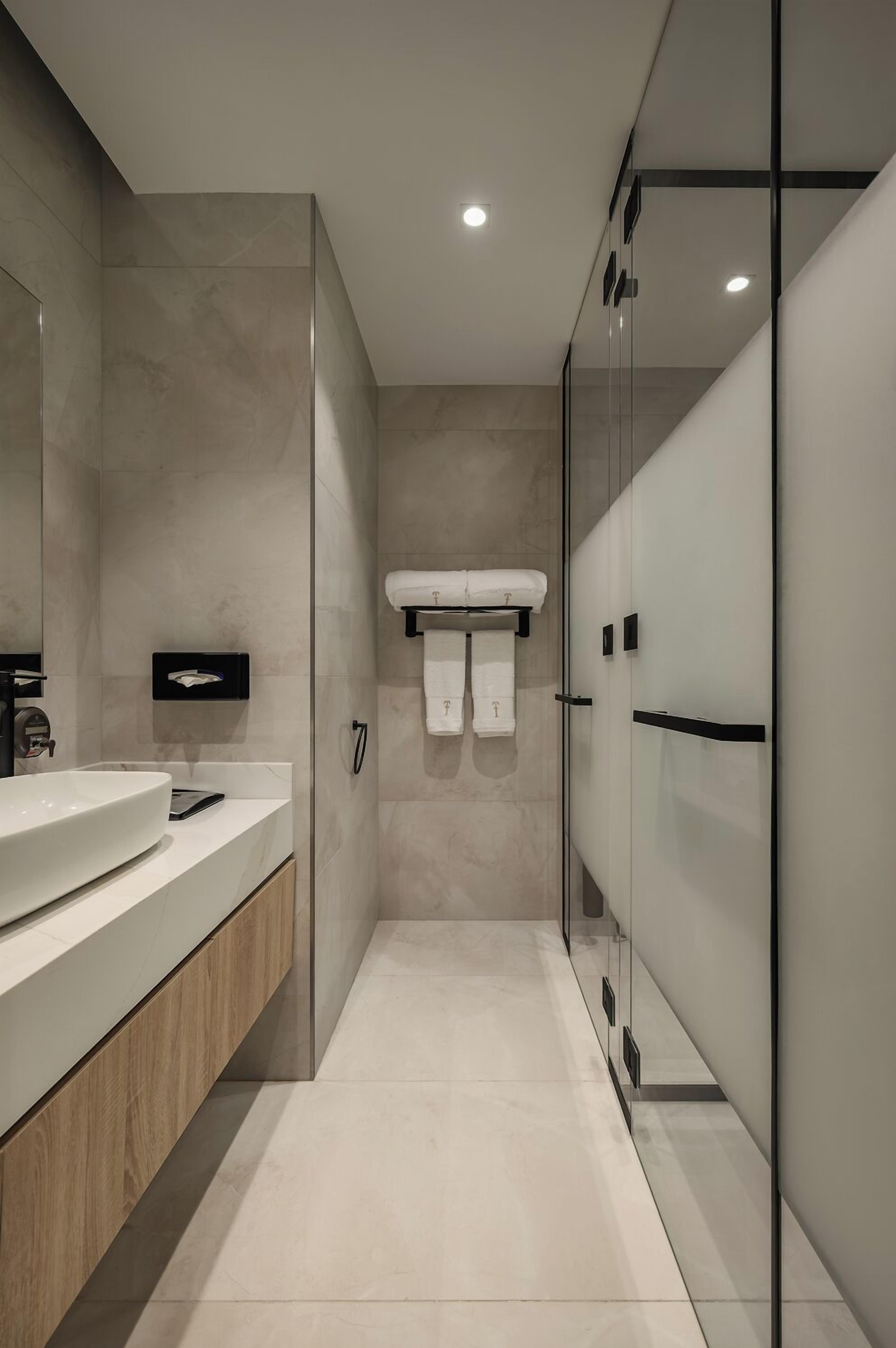 A modern bathroom with a large mirror, a sink, and a glass shower enclosure.