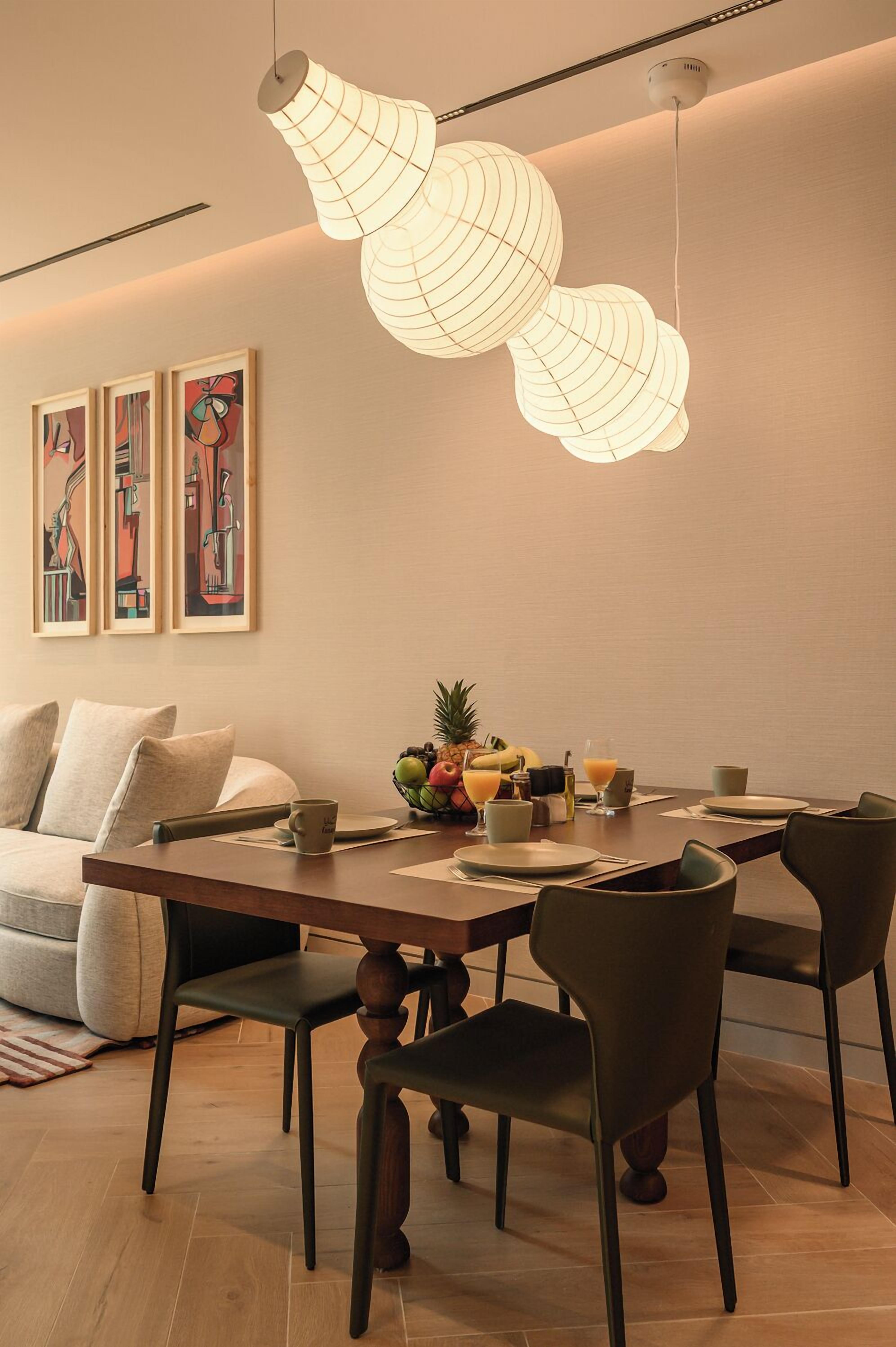 A dining area with a wooden table, modern chairs, and a unique hanging light fixture.