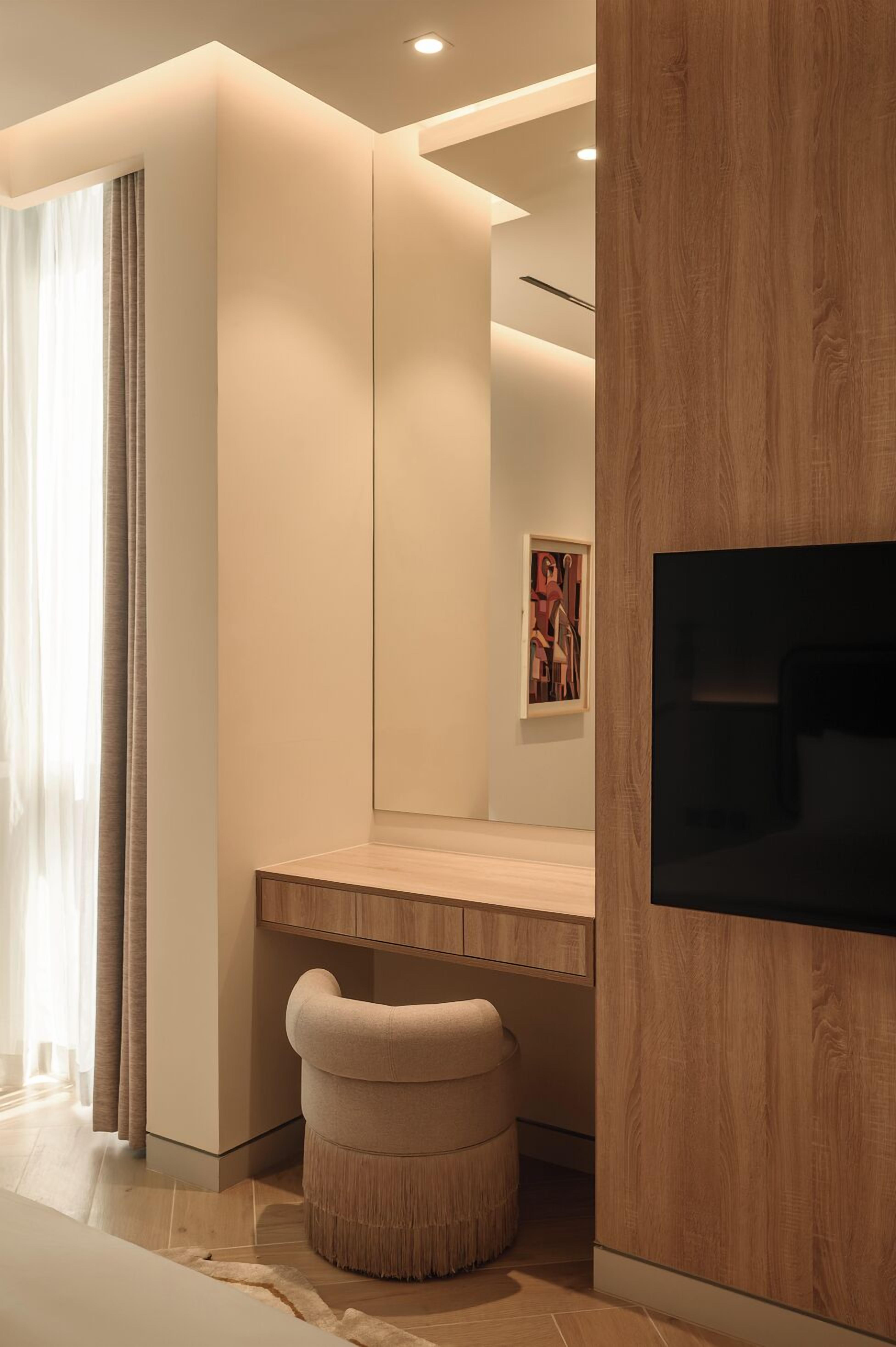 A modern bathroom with a wooden vanity, a mirror, and a television mounted on the wall.