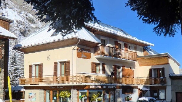 A two-story building with a balcony, a sign reading "INSTITUT DE BEAUTE," and a snow-covered roof.