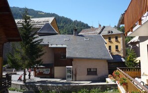 A view of a traditional village center with wooden buildings and a stone wall.