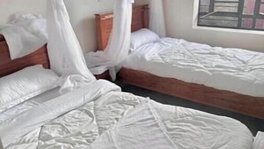 Une chambre avec deux lits, chacun doté d’une tête de lit en bois et de draps blancs.