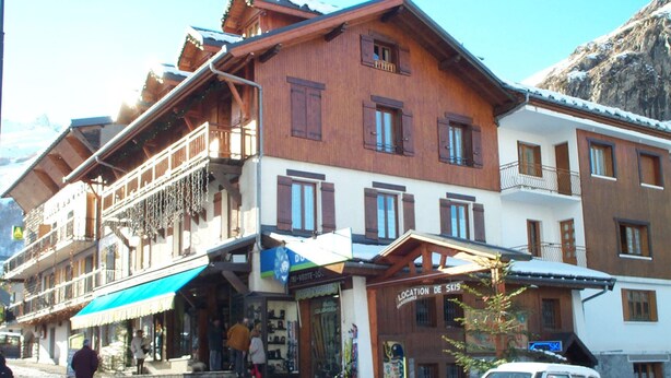 A multi-story building with wooden balconies, a ski location sign, and a storefront with a blue awning. - Apartment for 5 people, pets allowed in Valloire (Valloire)