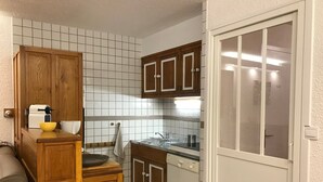 Eine kompakte Küche mit Holzschränken, einem Spülbecken, einem Herd und einem Fenster mit satiniertem Glas.