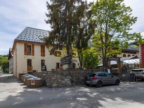 A building with a stone wall entrance, a parked car, and a sign for a restaurant.