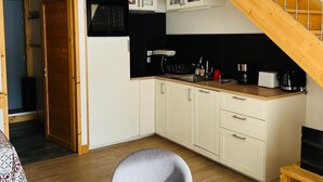 A compact kitchen with white cabinets, a wooden staircase, and a built-in oven. - Triplex 3 rooms with loft, 6 people, terrace, private parking (Valloire)