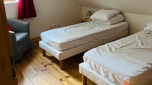 A room with two single beds, a chair, and a window with red curtains. - Triplex 3 rooms with loft, 6 people, terrace, private parking (Valloire)