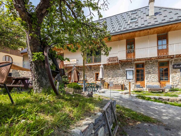 A rustic building with a stone facade, wooden balconies, and outdoor seating areas.