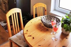 Una mesa de madera para comer con una cesta tejida, dos sillas y una planta en maceta.