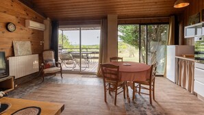 A wooden interior with a dining table, chairs, a TV, and a kitchen area.