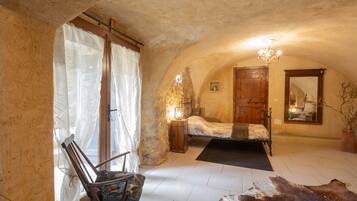 Une chambre à coucher rustique avec un lit, une chaise, un lustre et un grand miroir.