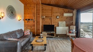 A cozy living room with a sofa, coffee table, TV, and a chair.