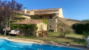 A villa with a swimming pool, stone walls, and a tiled roof.
