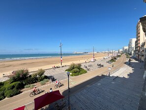 Eine Küstenstadt mit Strand, gepflasterter Promenade und Gebäuden.