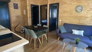Interior de madera con comedor, sofá y una mesita con una planta.