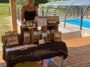 A table with various packaged goods, a person standing behind it, and a pool in the background.