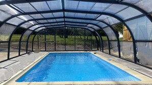 Una piscina techada con estructura de cubierta transparente.