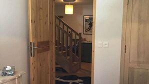 Une chambre avec une porte en bois, un lit, un tapis à motifs de vaches et un escalier menant à un coin cuisine.
