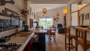 Een moderne keuken met een centraal eiland, houten stoelen en een eethoek met uitzicht.
