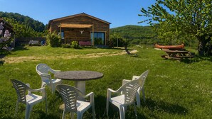 Een houten chalet met een veranda, omgeven door een gazon en een boom.