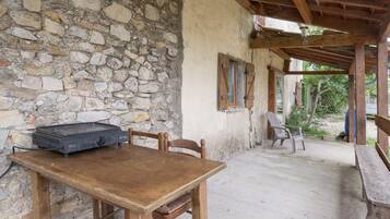 Un espace de restauration extérieur de style rustique, avec un mur en pierre, une table en bois et des chaises.