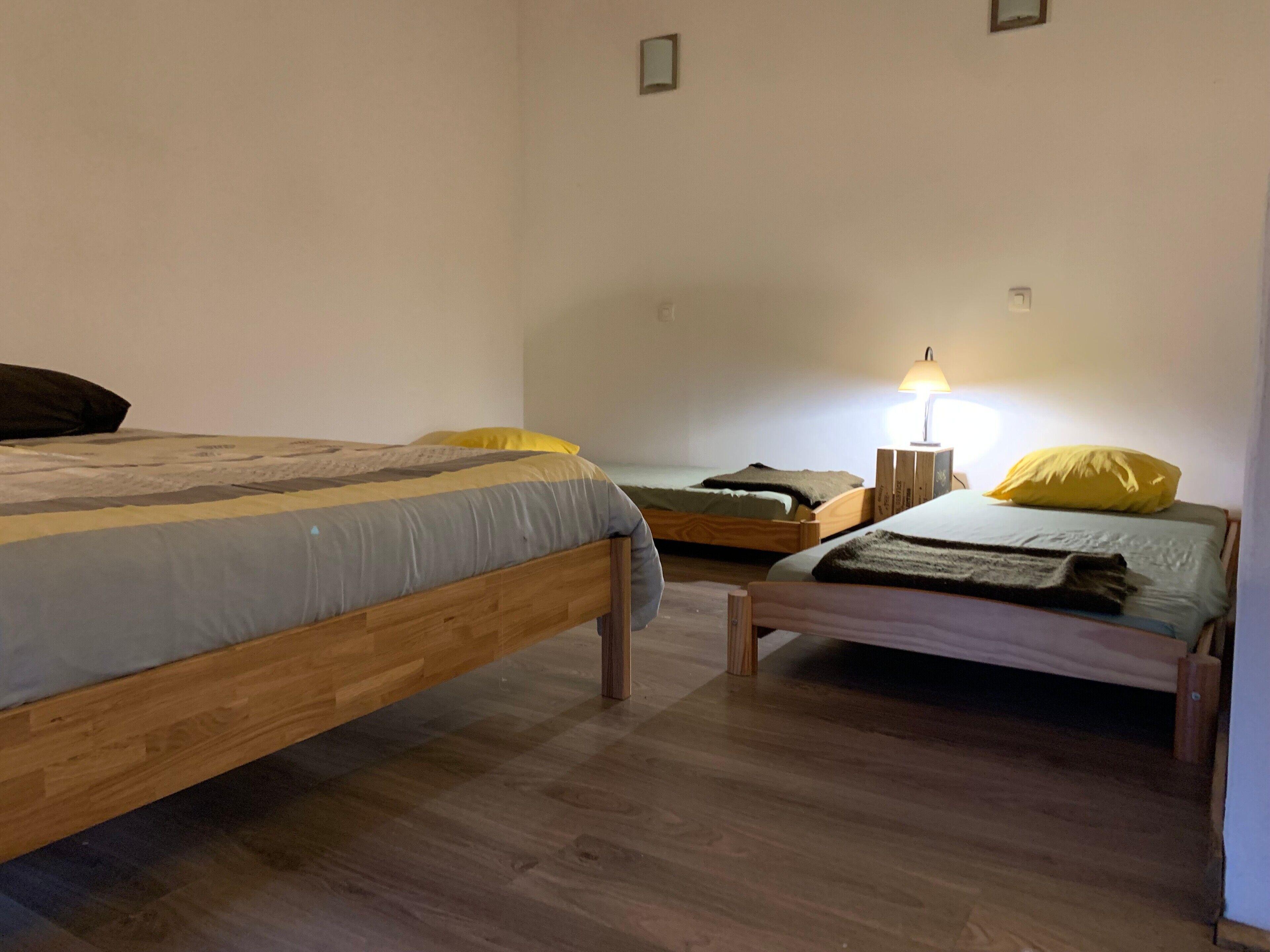 Une chambre avec deux lits en bois, une table de chevet avec une lampe et une petite table.