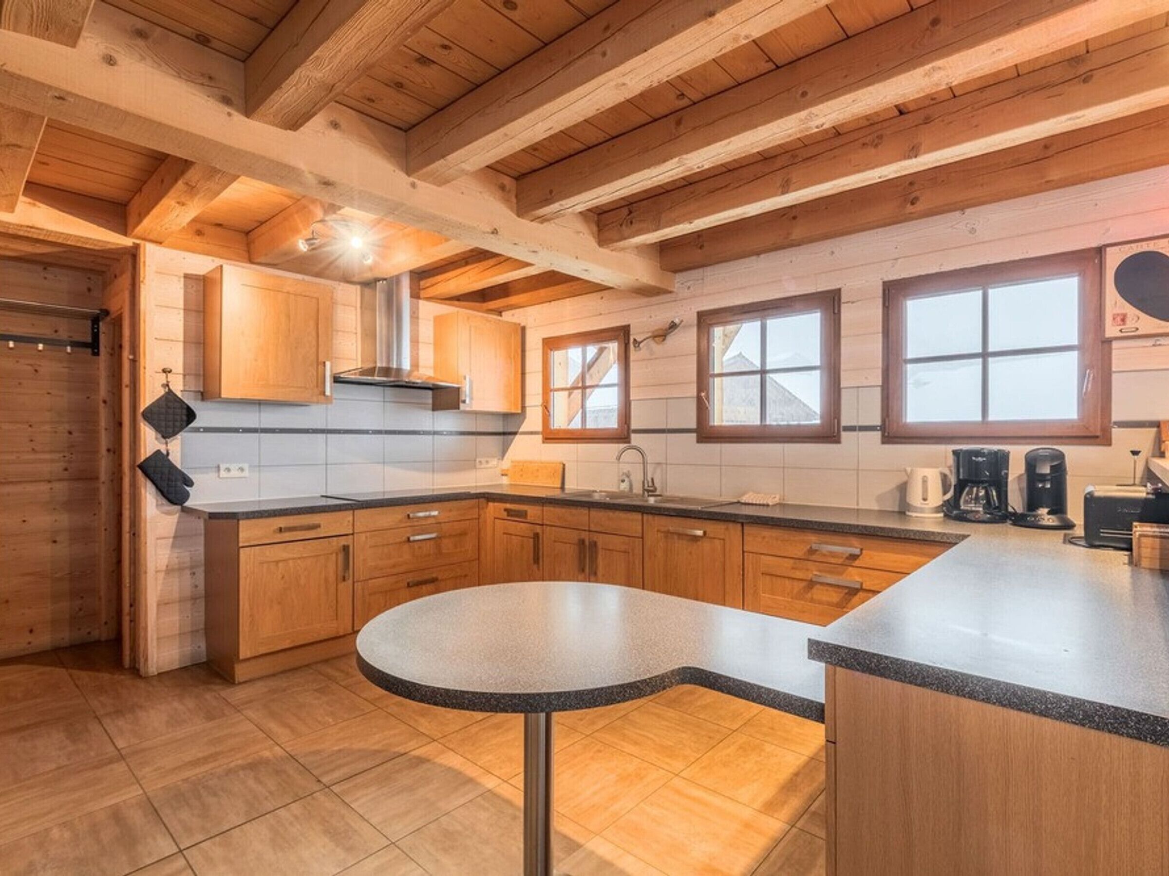 Une cuisine avec des meubles de rangement en bois, une table ronde et une fenêtre donnant sur un beau paysage.