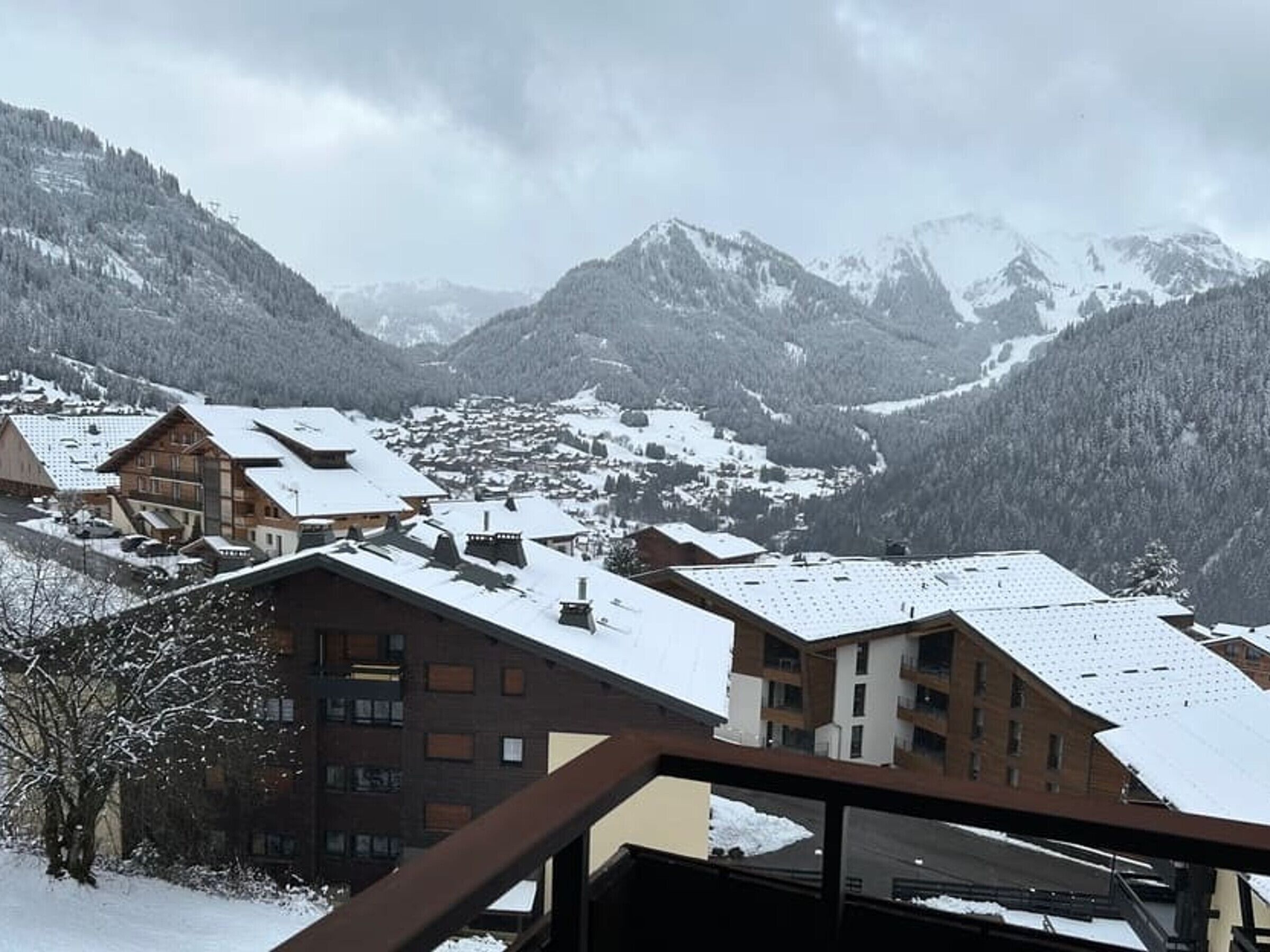 A snow-covered mountain village with traditional wooden buildings and a view of the surrounding peaks.