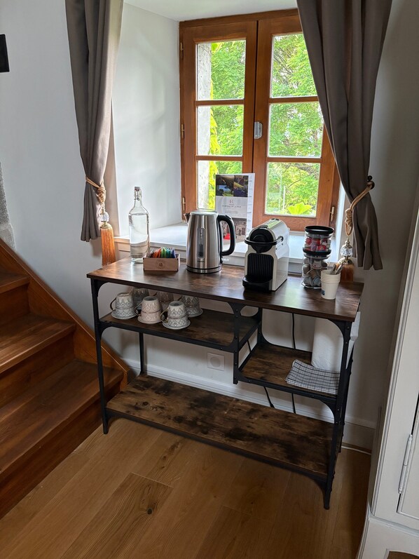 A kitchen with a wooden table, a kettle, a bottle, and a window with curtains. - Guest Room – Château de la Rive – Sleeps 10 (Cruet)