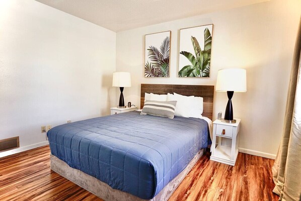 A hotel room with a large bed, two bedside tables, and two wall-mounted lamps.