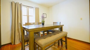 Un coin repas comprenant une table en bois, deux chaises, un banc et une plante en pot.