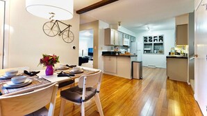 Una cocina moderna con piso de madera, un comedor con una mesa lista para dos personas y una bicicleta colgada en la pared.