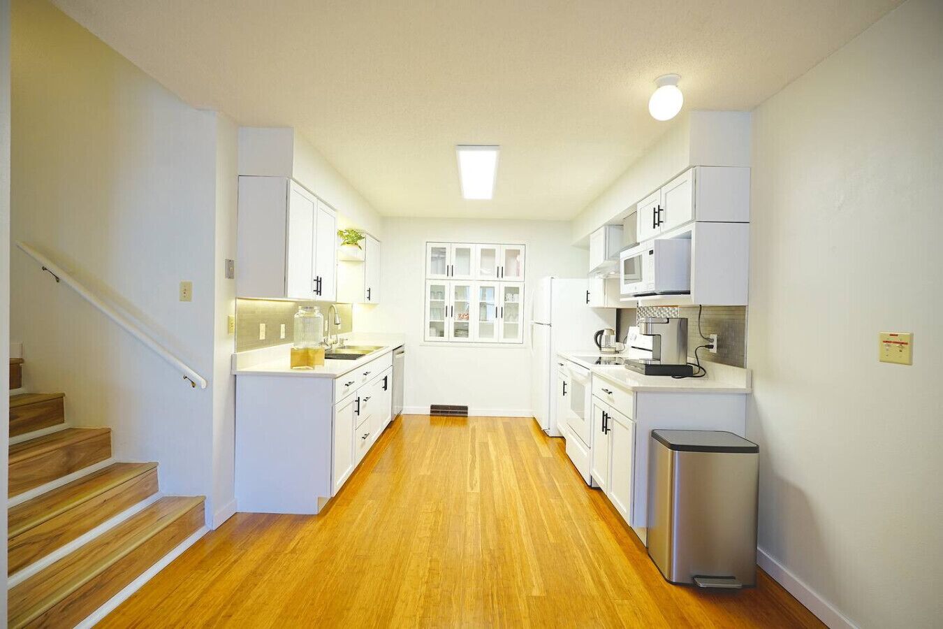A modern kitchen with white cabinetry, a stainless steel refrigerator, and a built-in oven.