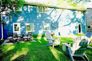 A blue house with a patio, a table, chairs, and a grill area.