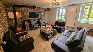 Un salon chaleureux avec une cheminée en pierre, un téléviseur et des fauteuils confortables.