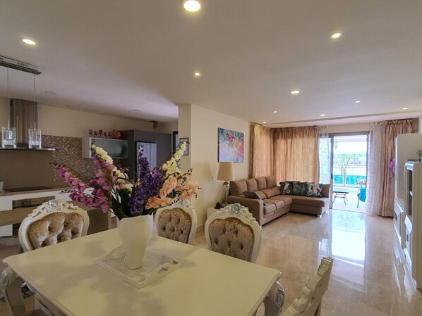 Amplia sala de estar con una mesa de comedor, sofás y una cocina al fondo.