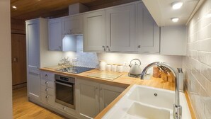 Uma cozinha moderna com armários cinza, bancada de madeira e forno embutido.