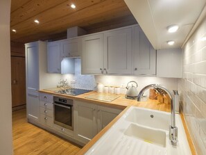 Eine moderne Küche mit grauen Schränken, einer Holz Arbeitsplatte und einem eingebauten Backofen.