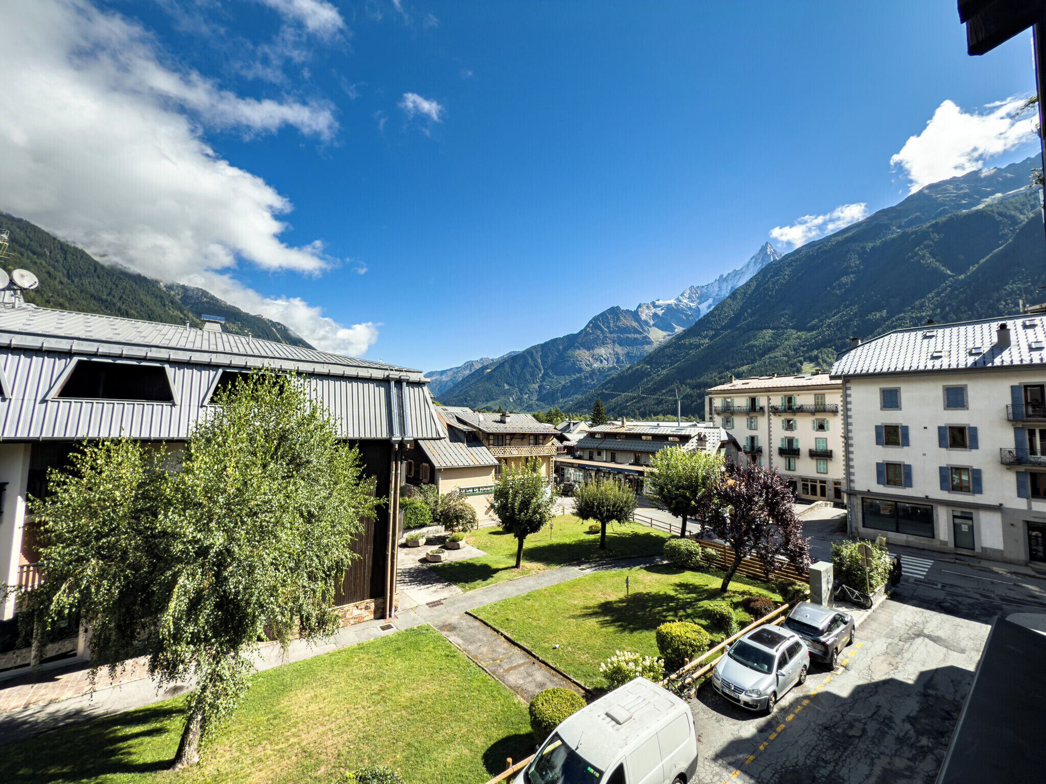 En hotellinnergård med utsikt över berg, parkerade bilar och en vit skåpbil.