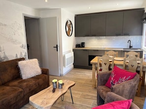 Una sala de estar moderna con un sofá marrón, una mesa de centro de madera y una zona de comedor con una mesa y sillas de madera.