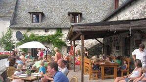An outdoor dining area with stone walls and wooden furniture. - Mobile home in Argences en Aubrac - 6 pax, Terrace (Argences-en-Aubrac)