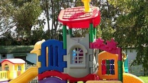A colorful play structure with multiple slides and climbing areas, surrounded by a grassy area and trees. - Mobile home in Argences en Aubrac - 6 pax, Terrace (Argences-en-Aubrac)
